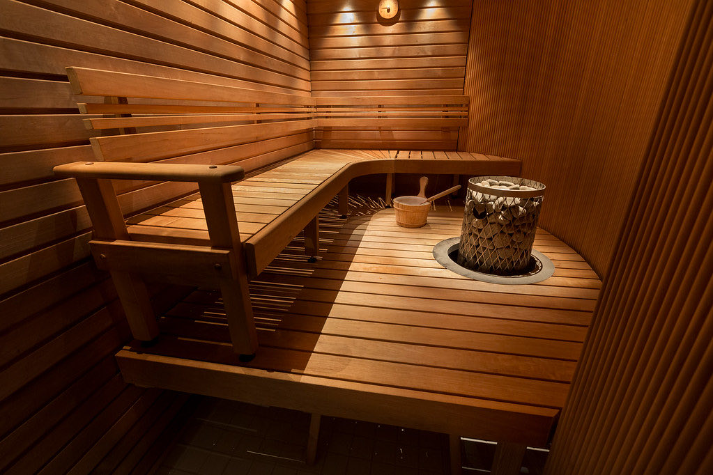 Warm beleuchtete Sauna mit Holzbänken und Saunaofen